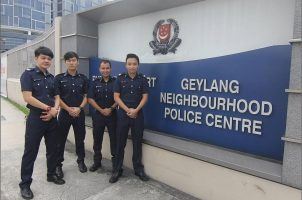 Police officers pose outside a police station in Geylang, Singapore