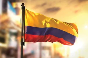 The flag of Colombia against a backdrop of the sun