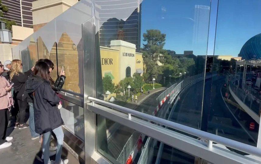 Vegas tourists photograph the MSG Sphere through glass panels. 