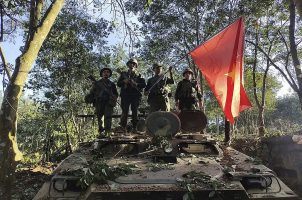 Myanmar National Democratic Alliance Army members pose on a tank they captured from the country's ruling military government