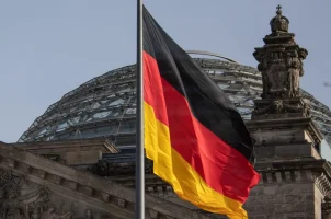 The German flag flies against a background of the dome of the Reichstag building in Berlin