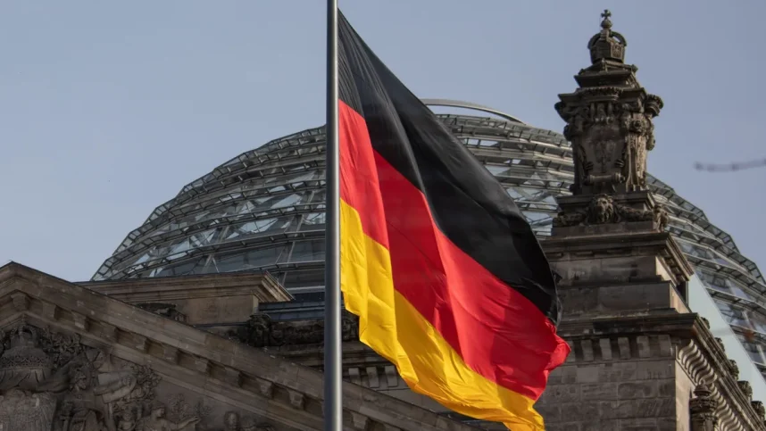 The German flag flies against a background of the dome of the Reichstag building in Berlin