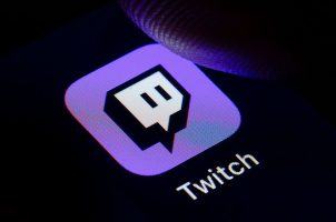 A user with his thumb hovering over the Twitch app icon on his mobile phone