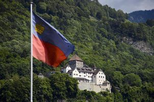 The flag of Liechtenstein flying against a background of Vaduz Castle